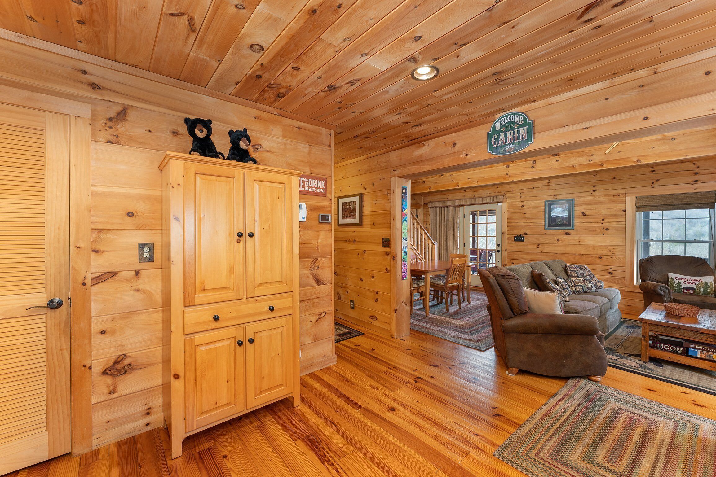 A cabin interior with wooden walls, a wooden cabinet, a sofa, a chair, and a coffee table.
