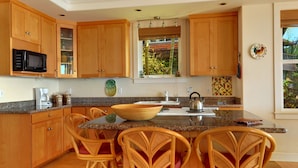 Una cocina con armarios de madera, microondas, cafetera y una isla grande con sillas.