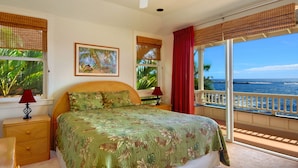 Un dormitorio con una cama grande, dos mesitas de noche con lámparas, una ventana con vista al mar y un cuadro en la pared.