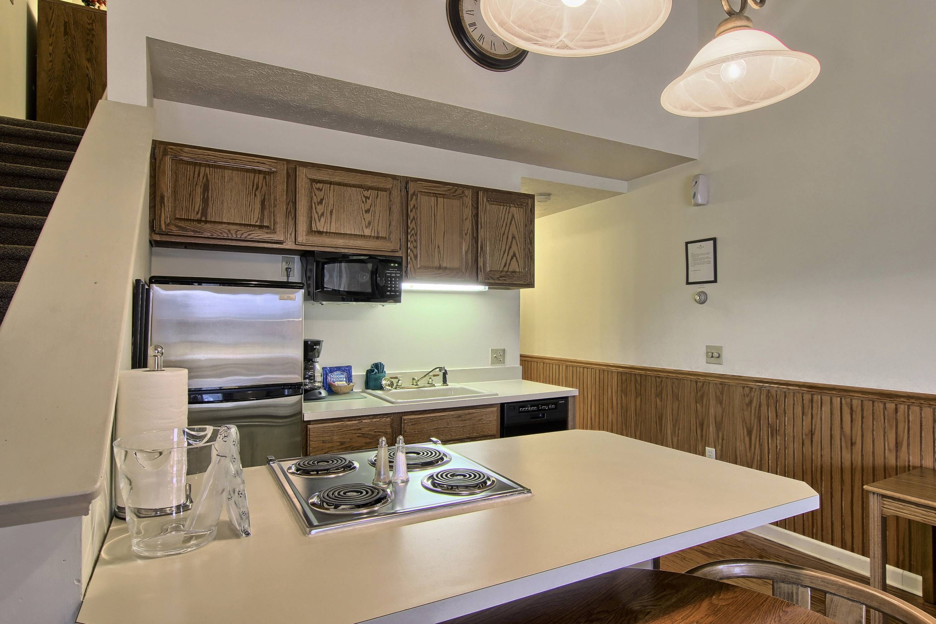 A kitchen with wooden cabinets, a stainless steel refrigerator, a microwave, a stove, and a sink.