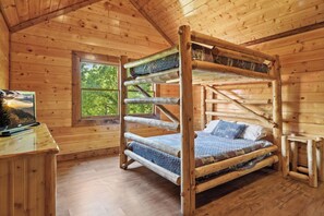 A wooden bunk bed with a television on a desk, a window with a view of trees, and a wooden floor. - Cabin w/views-Indoor Pool-Theater-Game Room (Cosby)