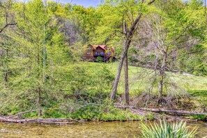 A house surrounded by dense greenery and a small body of water.
