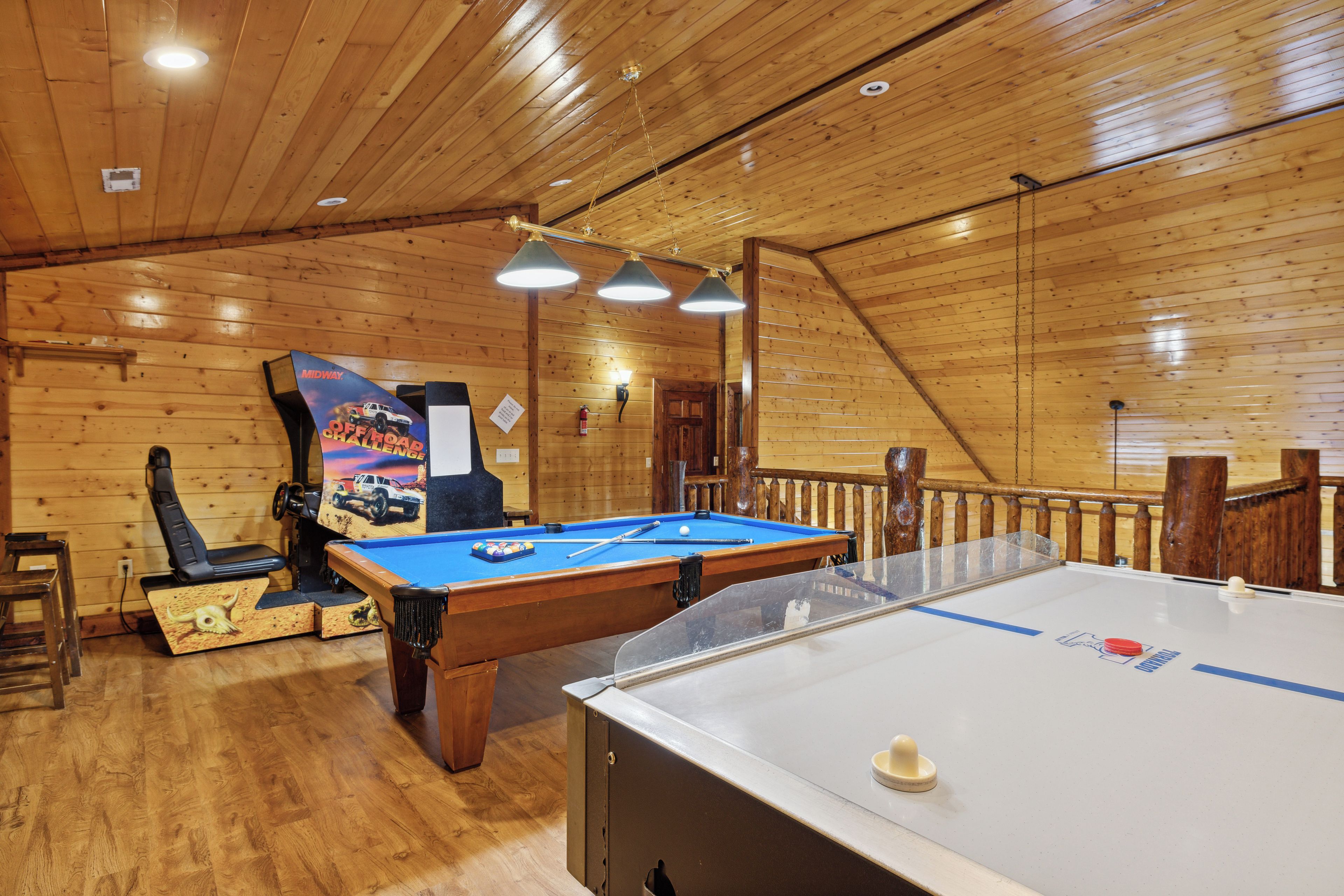 A pool table with a blue felt surface, a foosball table, and a poster on the wall.
