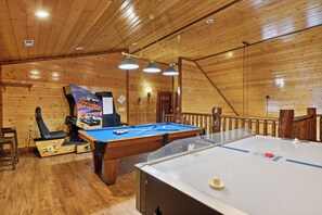 Een pooltafel met een blauwe viltkleed, een tafelvoetbaltafel en een poster aan de muur.