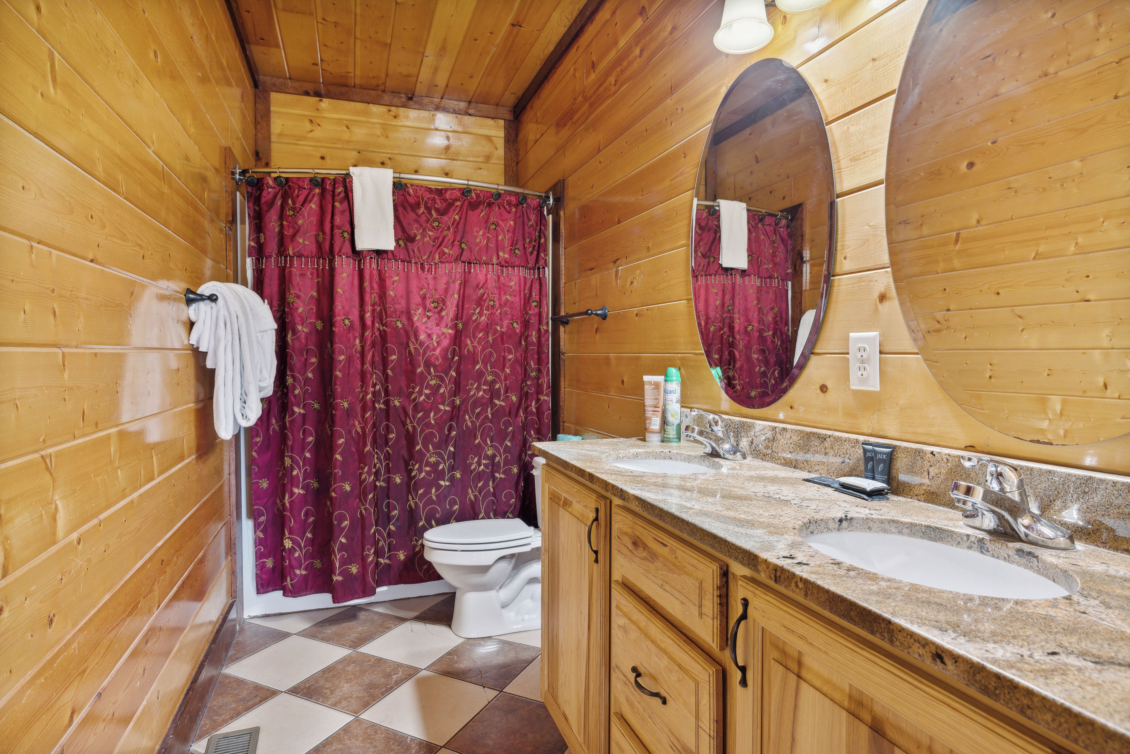 Un baño de madera con inodoro, lavamanos y cortina de ducha.
