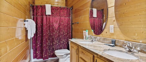 Un baño de madera con inodoro, lavamanos y cortina de ducha.
