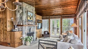Una sala de estar acogedora con chimenea de piedra, paredes de madera, un sofá y un televisor.