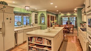 Una cocina con isla central, estanterías empotradas y un comedor con mesa y sillas.