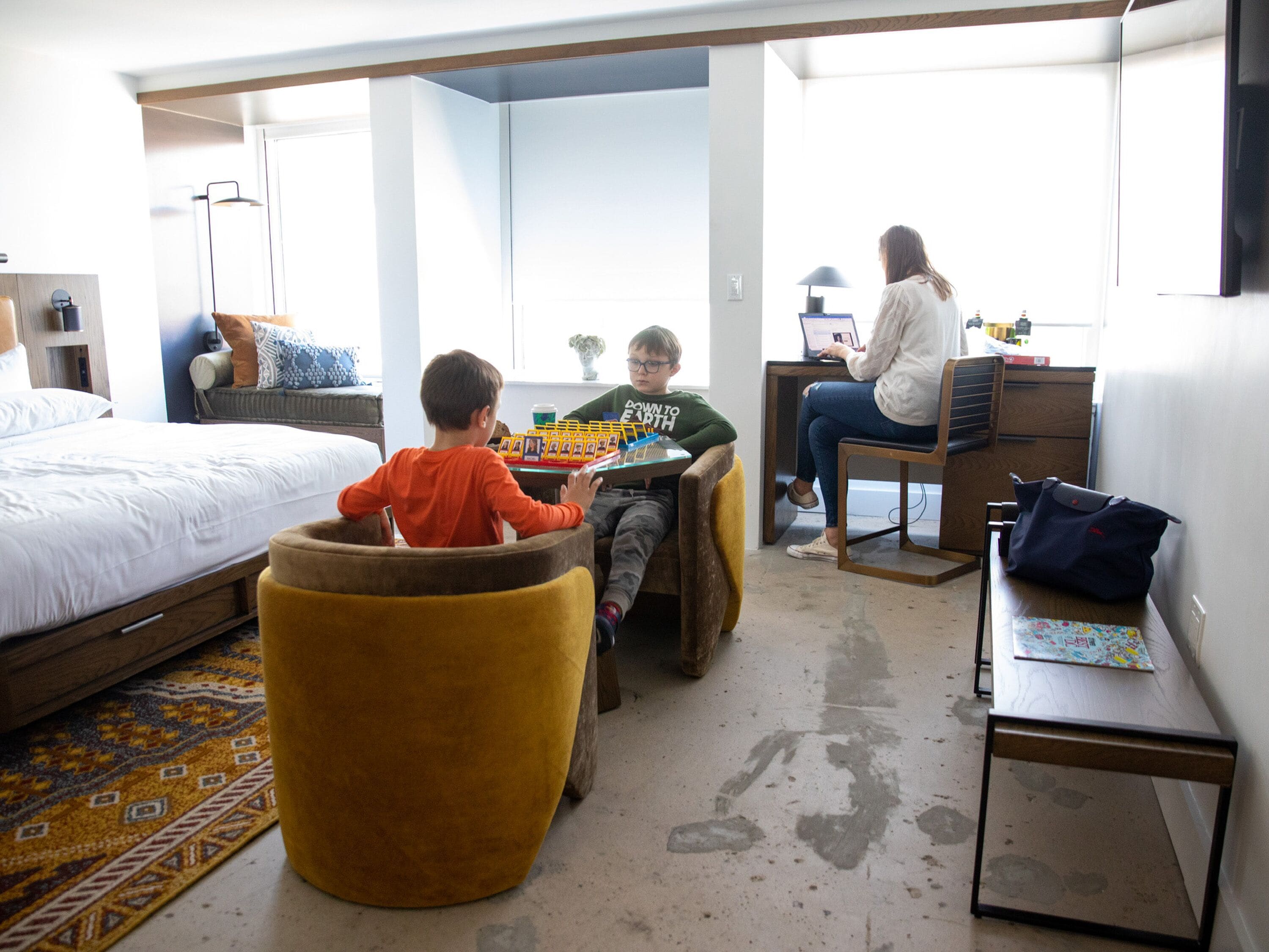 A modern hotel room with a bed, a desk, a chair, and a sofa.