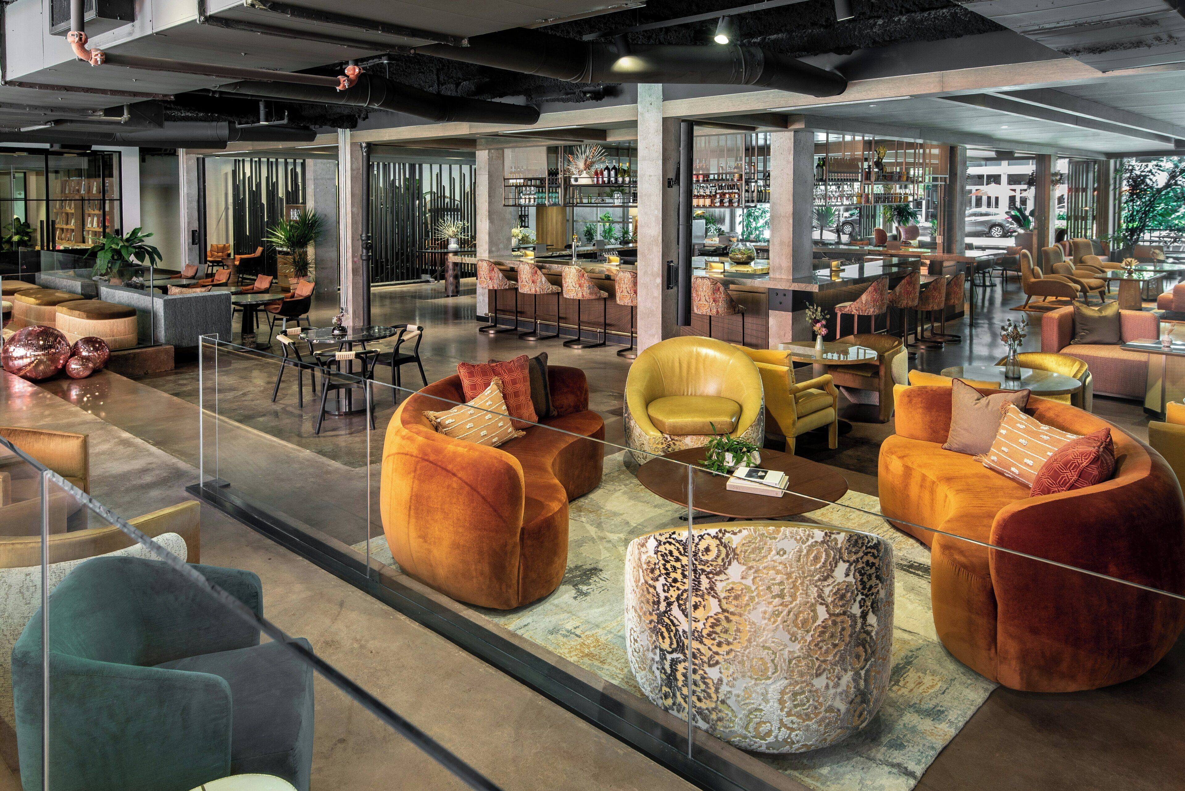 Eine großzügige Lobby mit mehreren Sitzbereichen, einer Bar und Blick auf die Straße.