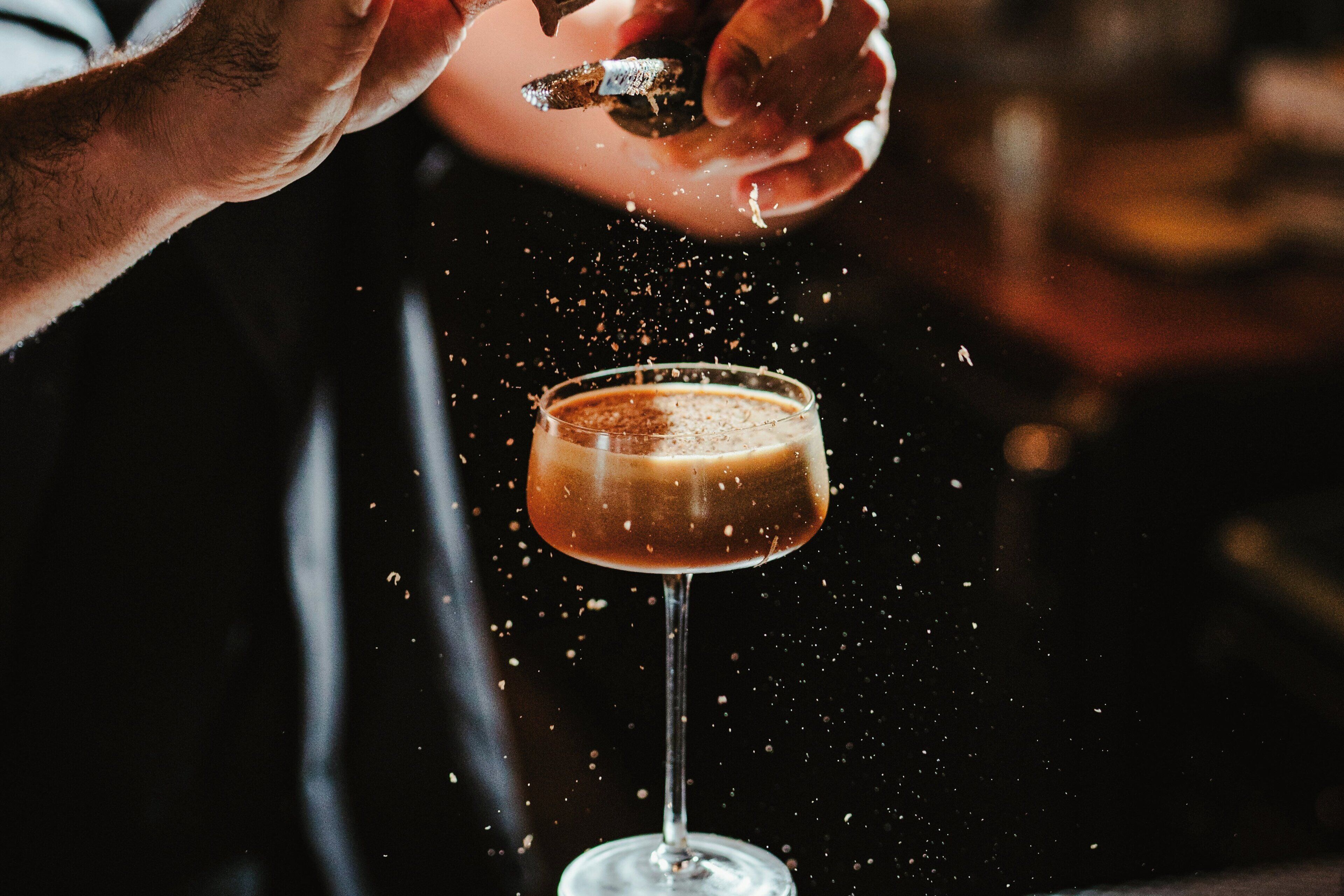 Une personne en train de verser une boisson dans un verre, l’accent étant mis sur l’action et le verre.
