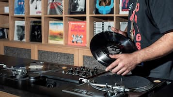 A person holding a vinyl record near a turntable with multiple controls.