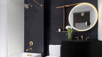 Un baño moderno con un lavamanos negro, inodoro blanco y bañera.