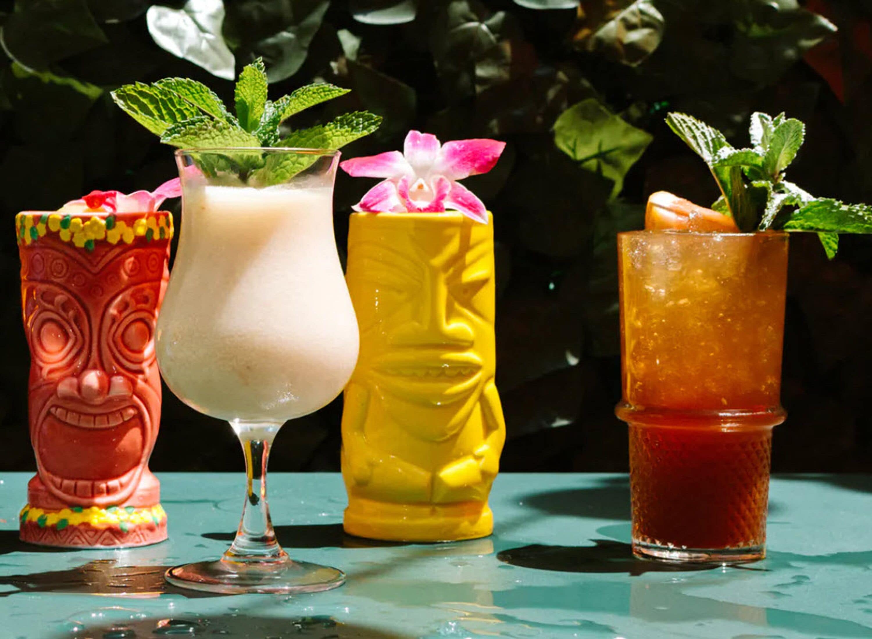 Three drinks in colorful glasses with decorative elements.