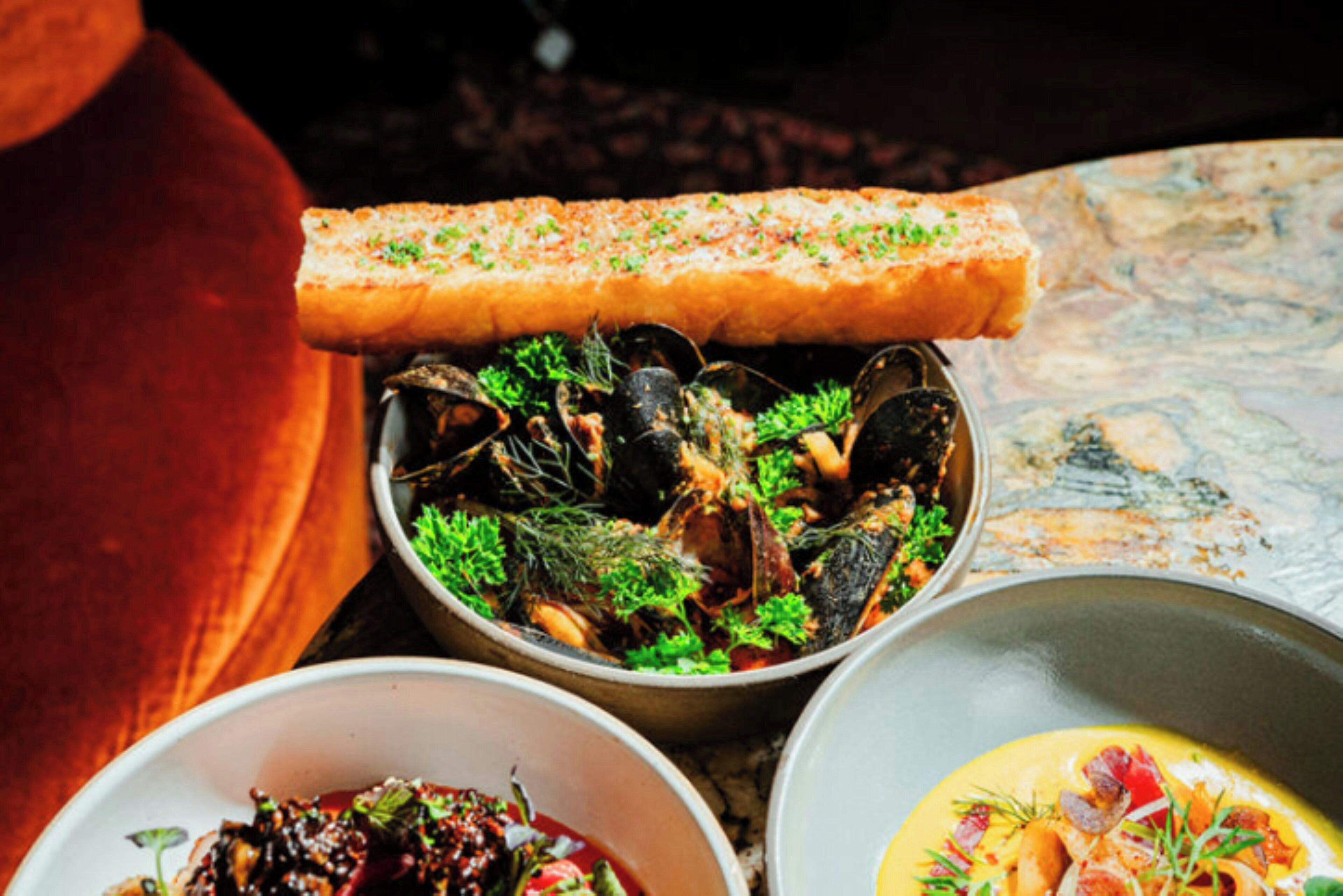 Un plat de fruits de mer composé de moules, d’un morceau de poisson et d’une sauce.