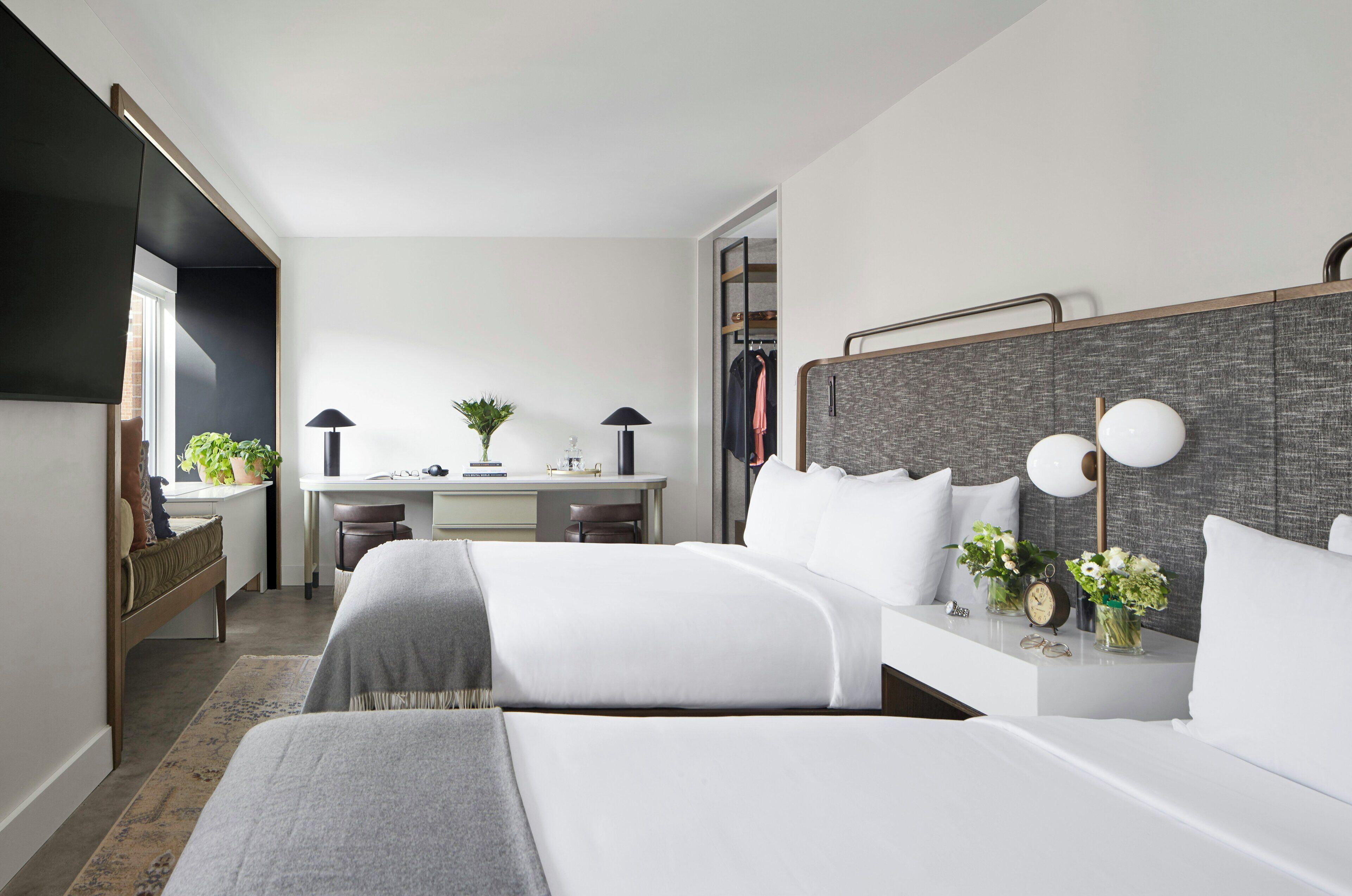 A hotel room with a bed, bedside tables, a desk, and a wardrobe.