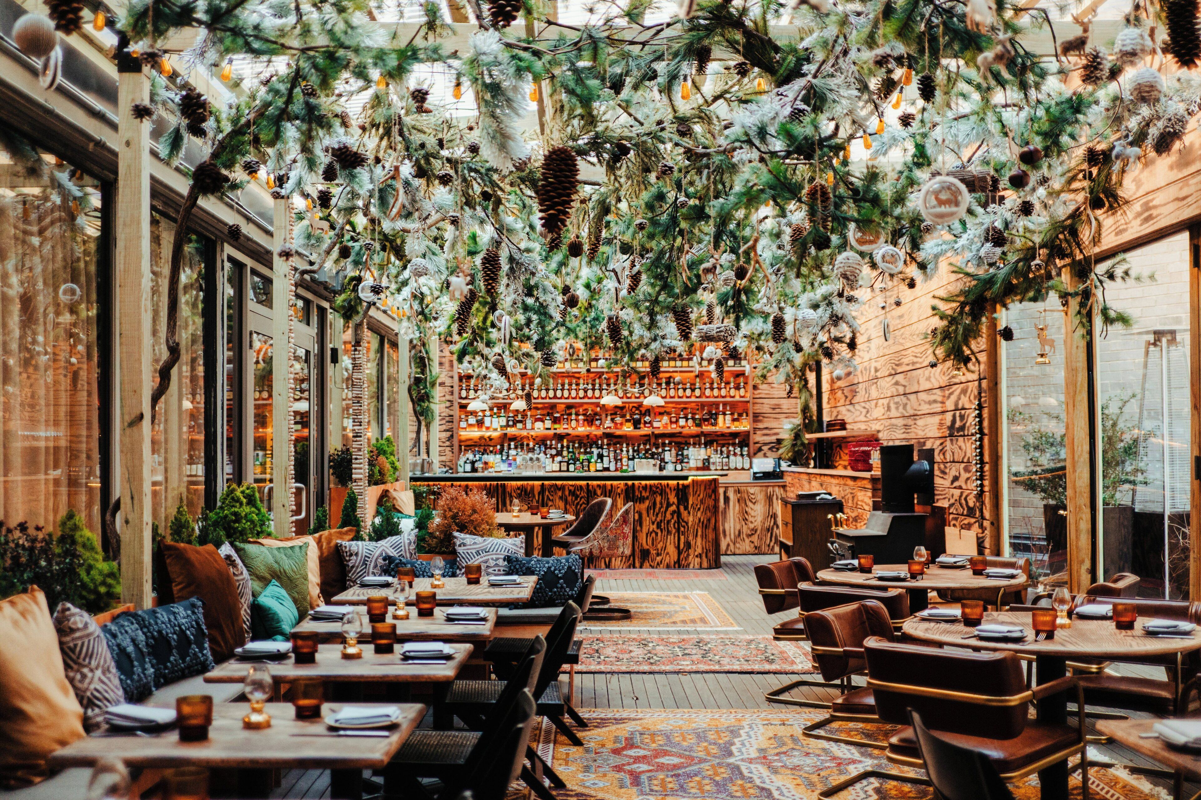 An indoor dining area with tables, chairs, and a bar in the background.