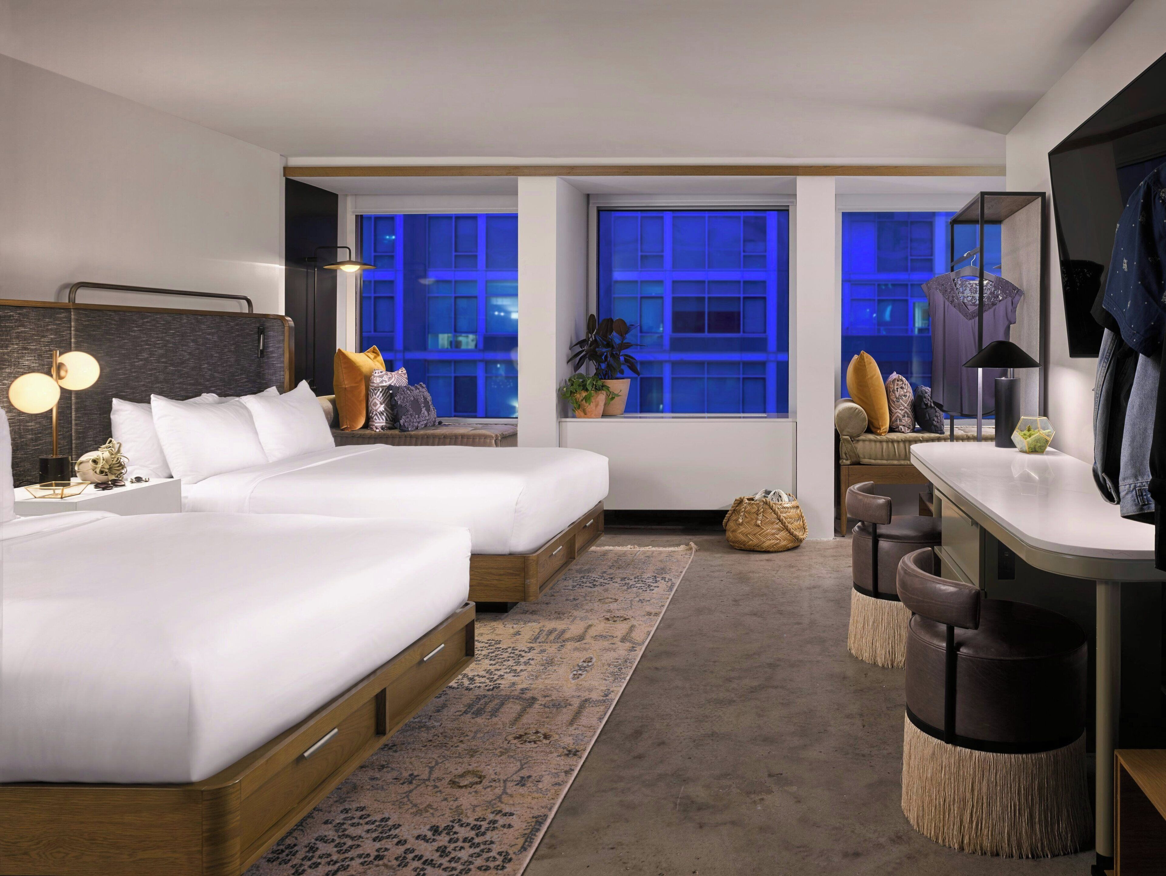 A hotel room with two beds, a sitting area with a sofa, a small table, and a TV.