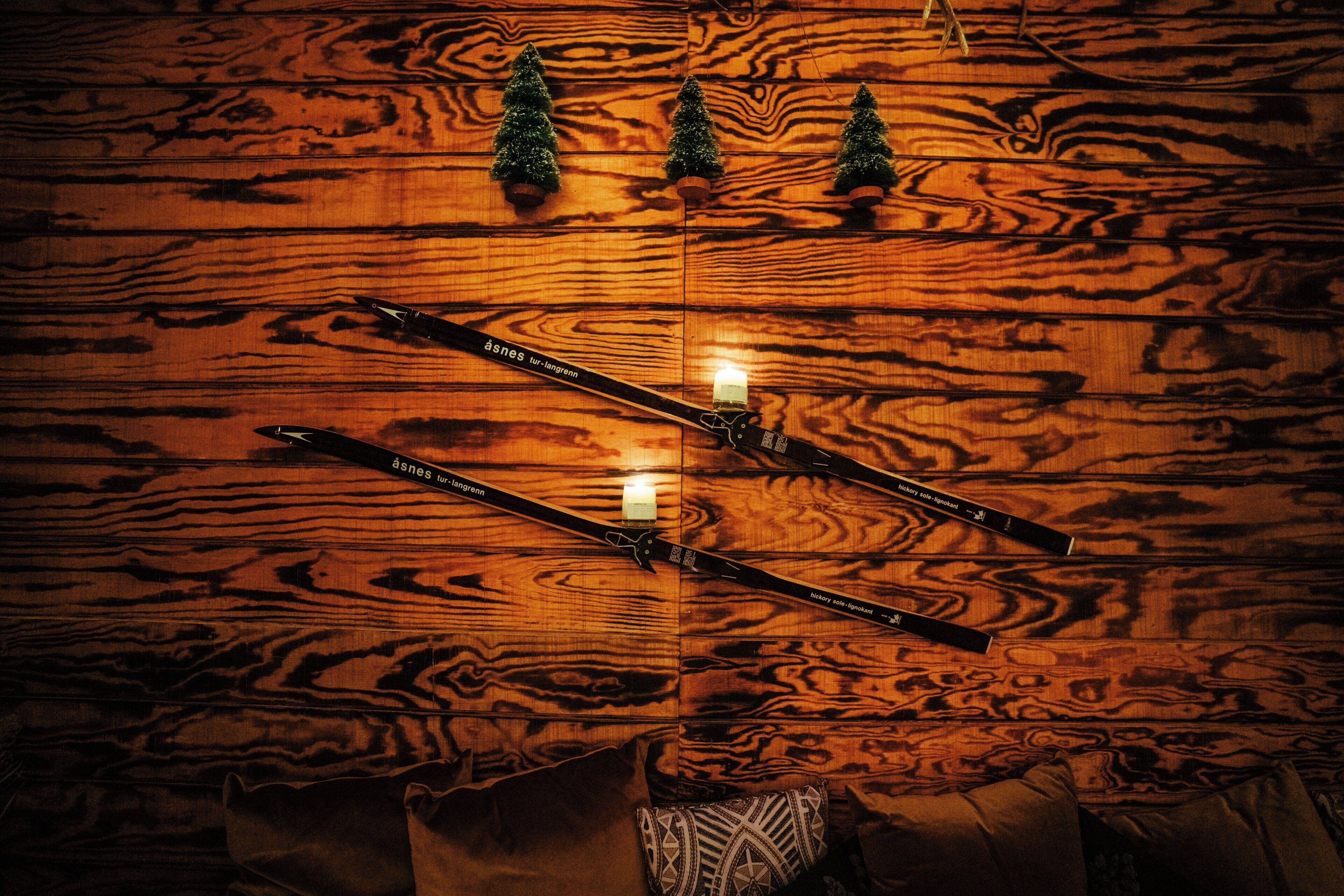 A wooden floor with two skis crossed over each other and a candle between them.