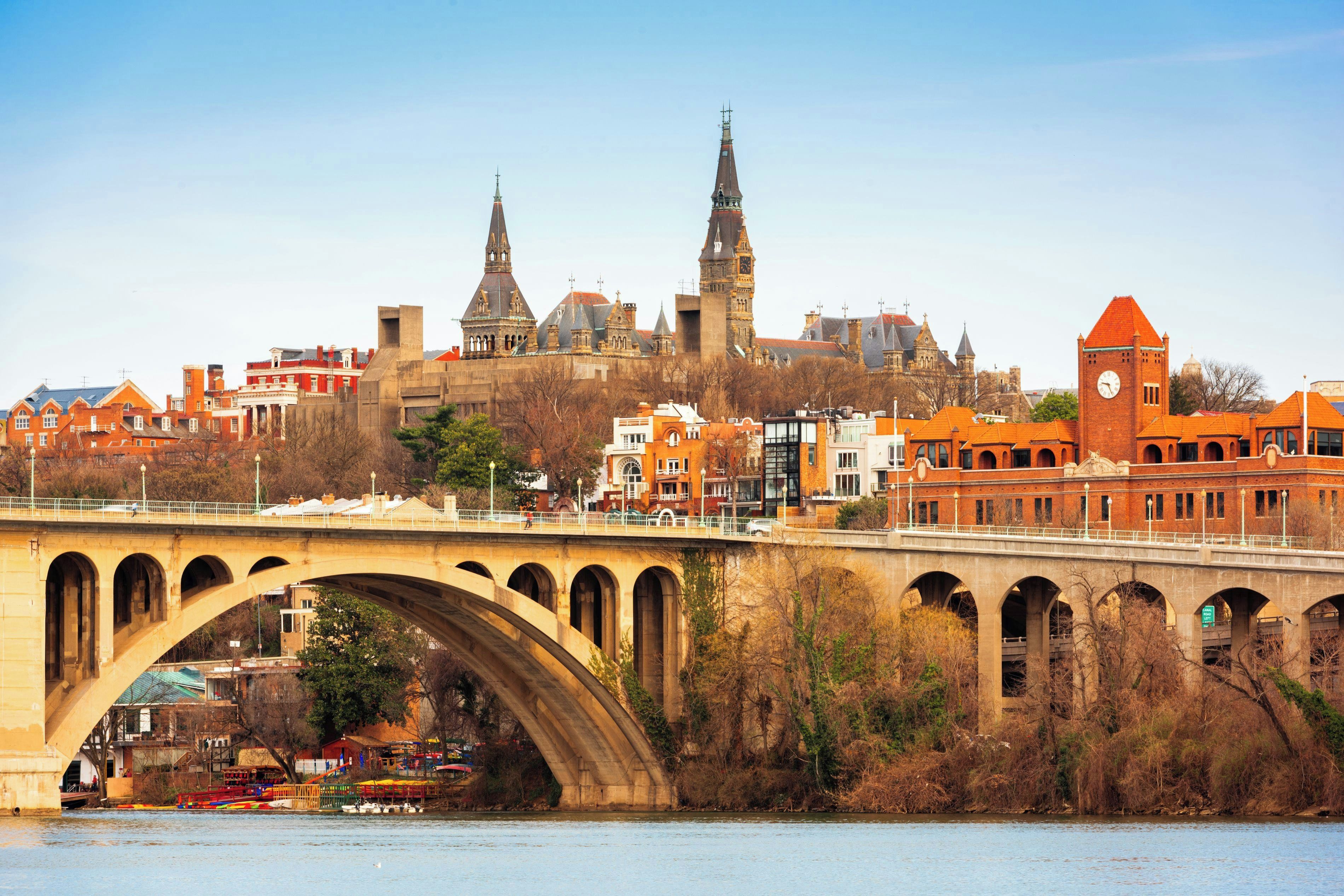 A historic bridge with arches spanning over a river, leading to a cityscape with notable buildings and a prominent clock tower.
