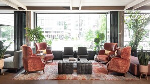 Un espacio lounge moderno con dos sofás, una mesa de centro y plantas en macetas.