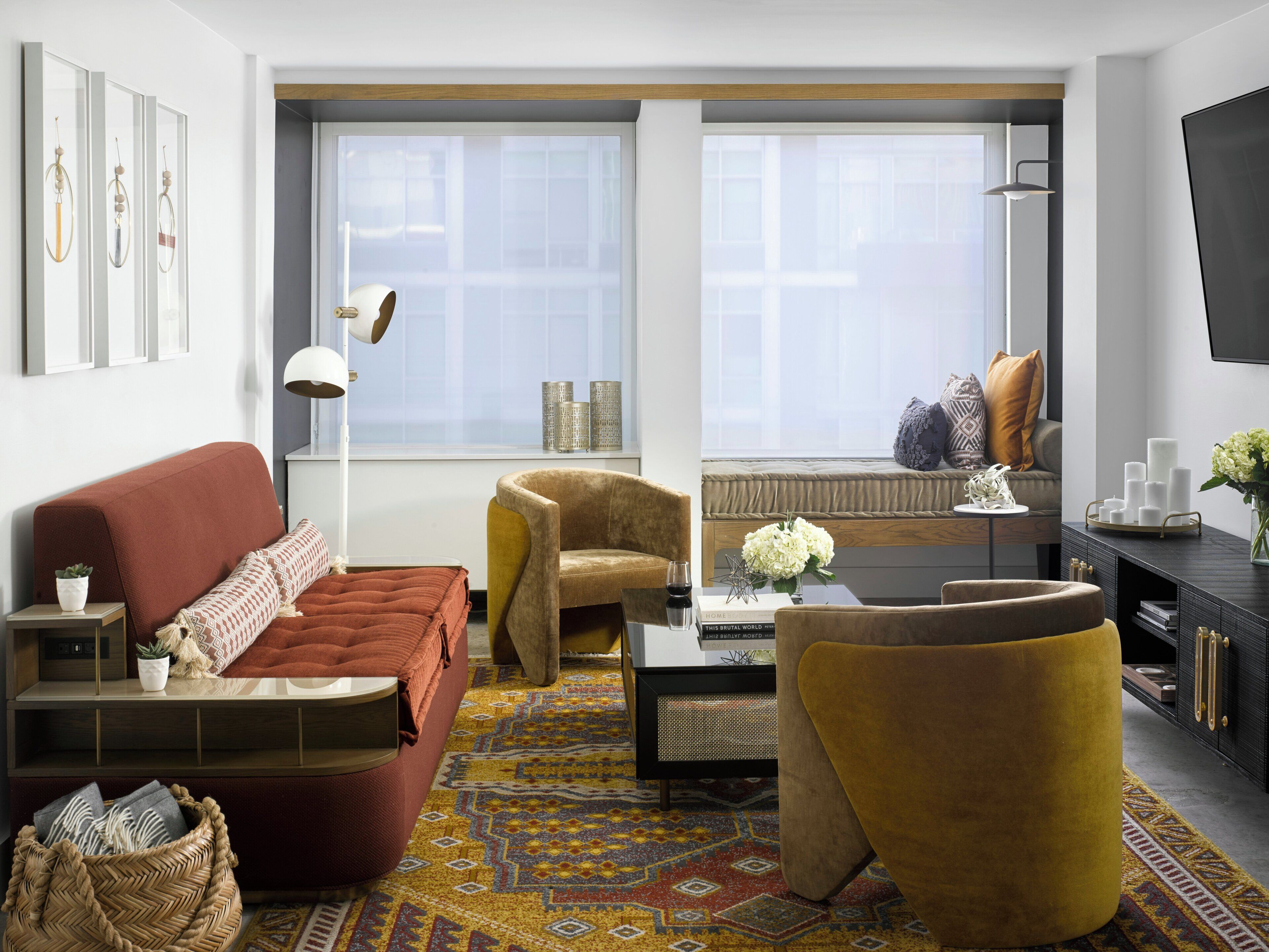 Un salon moderne comprenant un canapé, un fauteuil, une table basse et un tapis à motifs.
