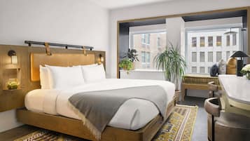 A modern hotel room with a large bed, a desk, and a view of the city.