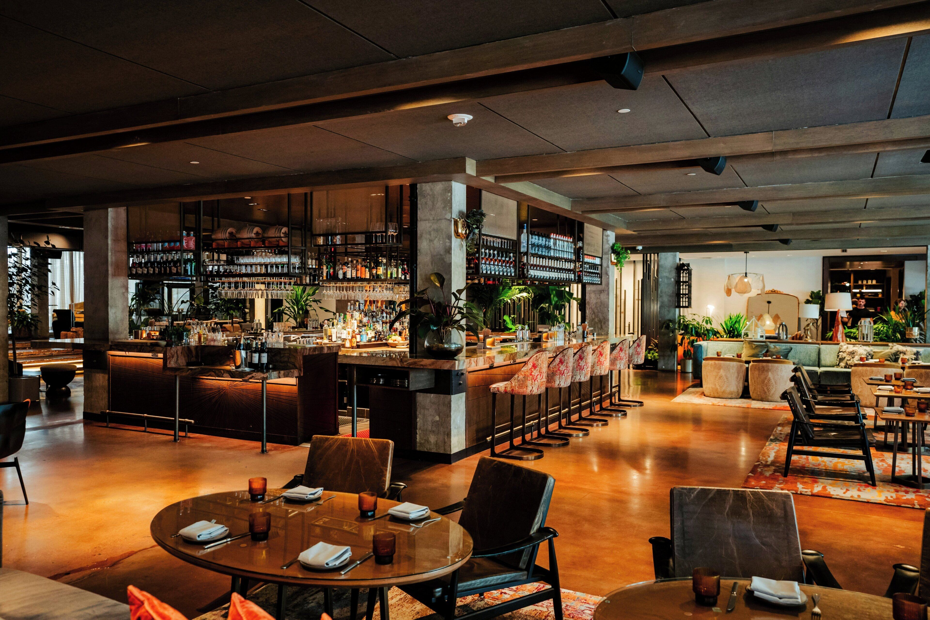 Zona de bar moderna con barra, asientos y una variedad de botellas y copas.