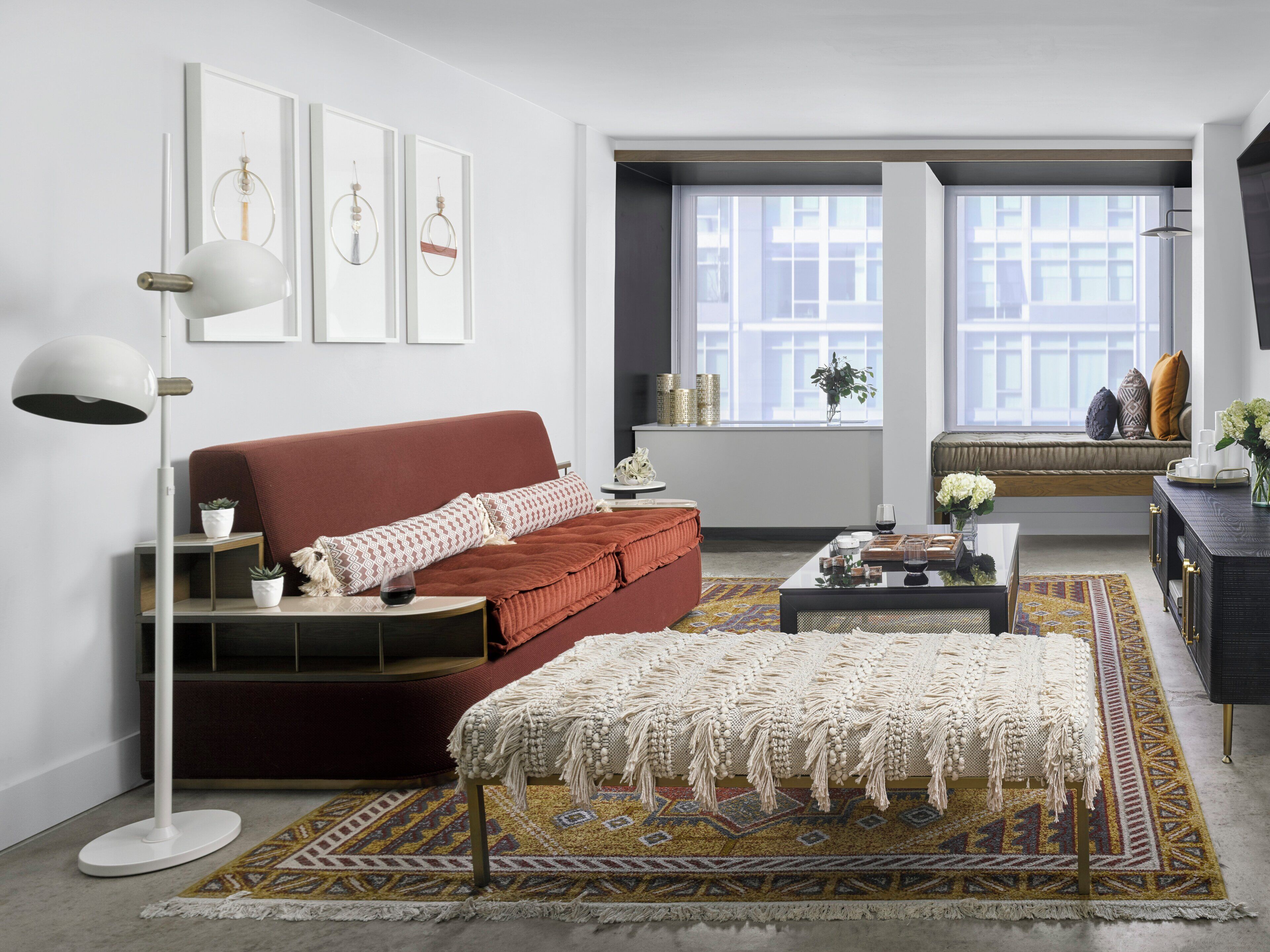A modern living room with a red sofa, a white floor lamp, and a patterned rug.