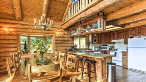 A wooden cabin interior with a dining area, kitchen, and a large window. - 13 Mi to Mt Shasta: Log Home on 60 Acres! (McCloud)