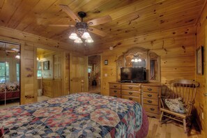 A wooden cabin bedroom with a bed, dresser, chair, and ceiling fan. - Creekside Cabin-Private Hot Tub-Firepit-Fishing (Cosby)