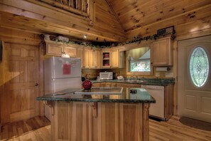 A wooden cabin kitchen with a refrigerator, microwave, sink, and a red kettle. - Creekside Cabin-Private Hot Tub-Firepit-Fishing (Cosby)