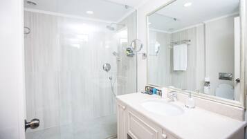 A modern bathroom with a glass-enclosed shower, a large mirror, and a white sink.
