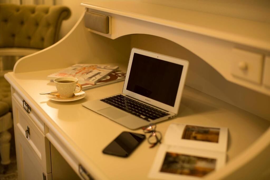A laptop on a desk with a cup of coffee, a smartphone, and some magazines.