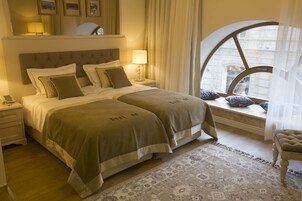 Een hotelkamer met een groot bed, een nachtkastje, een raam met uitzicht op gebouwen en een stoel.