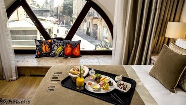 Habitación de hotel con cama, ventana con vistas a la ciudad y bandeja de desayuno en el alféizar.