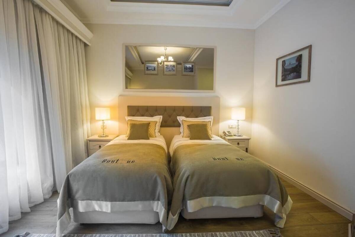 A double room with two beds, a large mirror above, and a chandelier.