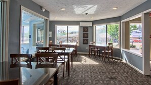 A restaurant interior with large windows, wooden tables and chairs, and a patterned carpet. - Pointes North Inn 109 | Downtown Charlevoix | Indoor pool (Charlevoix)