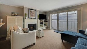 A living room with a fireplace, a television, and a view of a balcony.