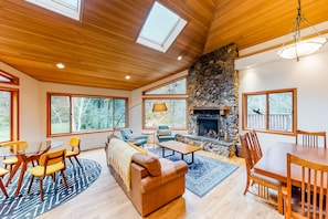Cozy living area with a stone fireplace, comfortable seating, and large windows offering views of the surrounding landscape.