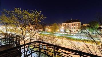 A night view of a building with a balcony, surrounded by trees and streetlights.