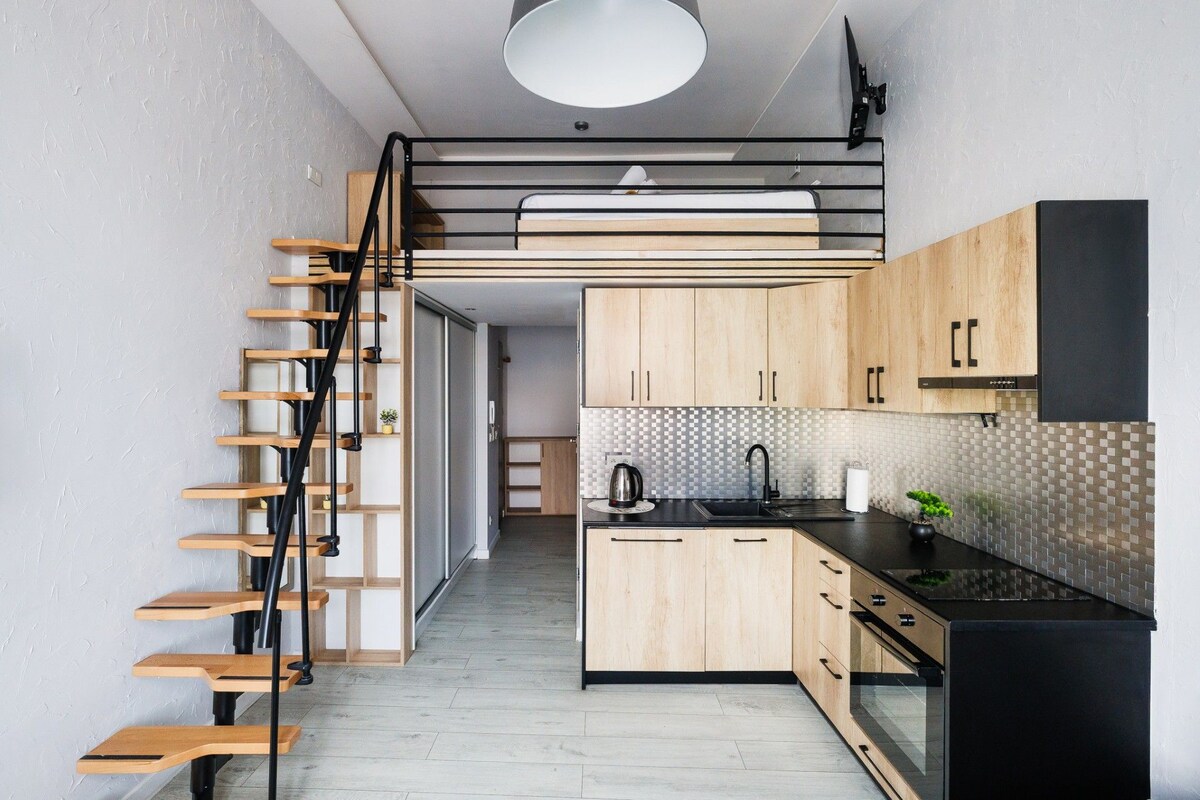 A compact kitchen with wooden cabinets, a black countertop, and a built-in stove.