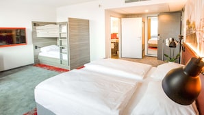 A hotel room with a large bed, a built-in wardrobe, a bathroom with a mirror, and a red carpet.