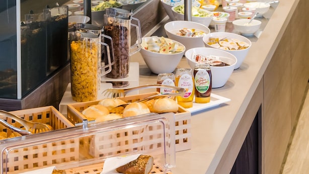 A buffet with various food items, including bread, salads, and beverages.