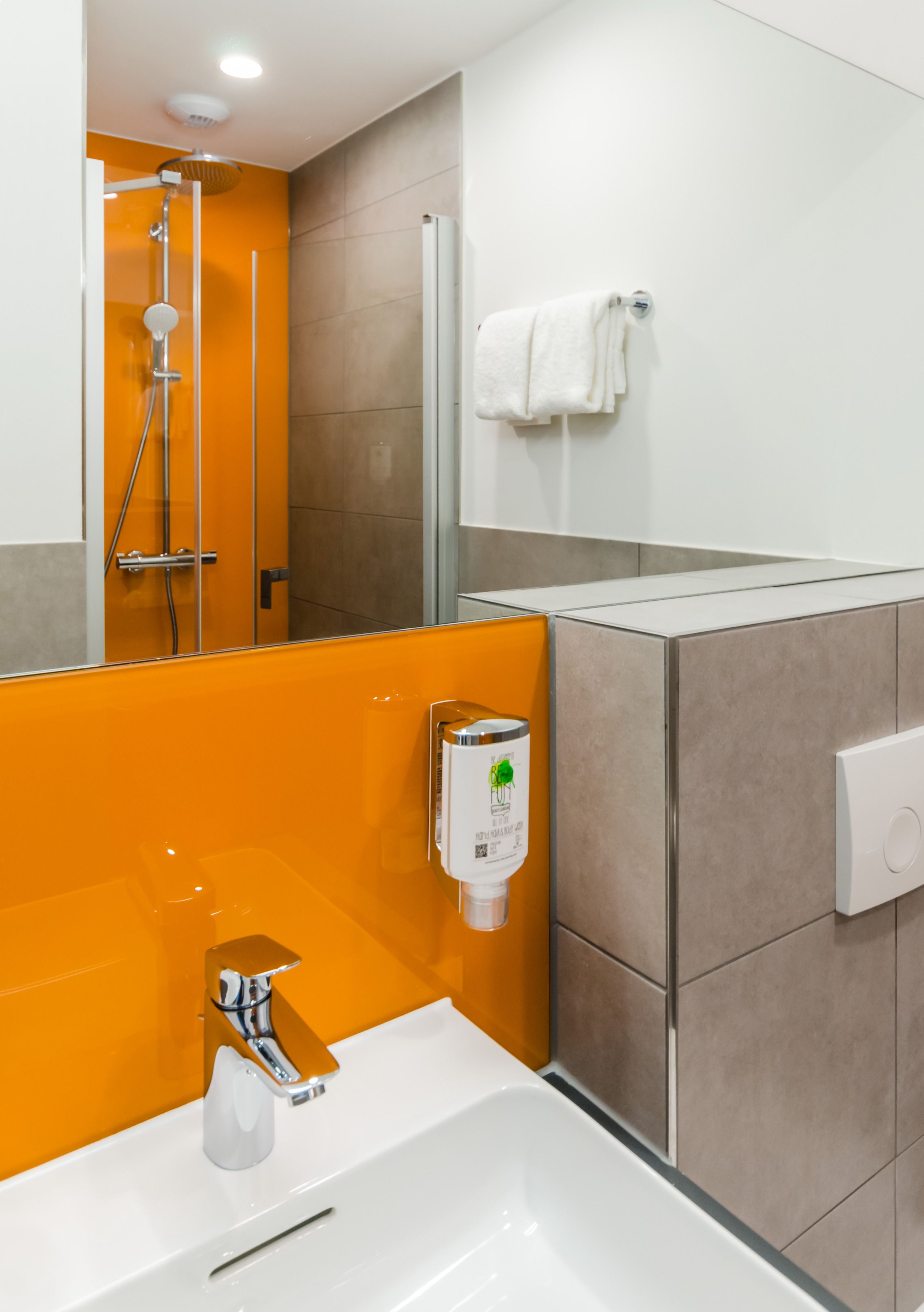 A modern bathroom with a white sink, a handheld showerhead, and a towel rack.