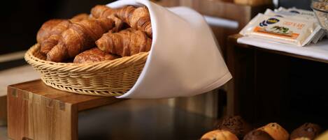 A breakfast buffet with a basket of croissants and a variety of muffins.