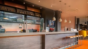 A modern bar area with a wooden counter, bar stools, and a menu display.