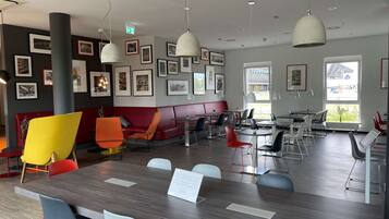A modern dining area with a mix of seating options including tables and booths, framed artwork on the walls, and pendant lighting.