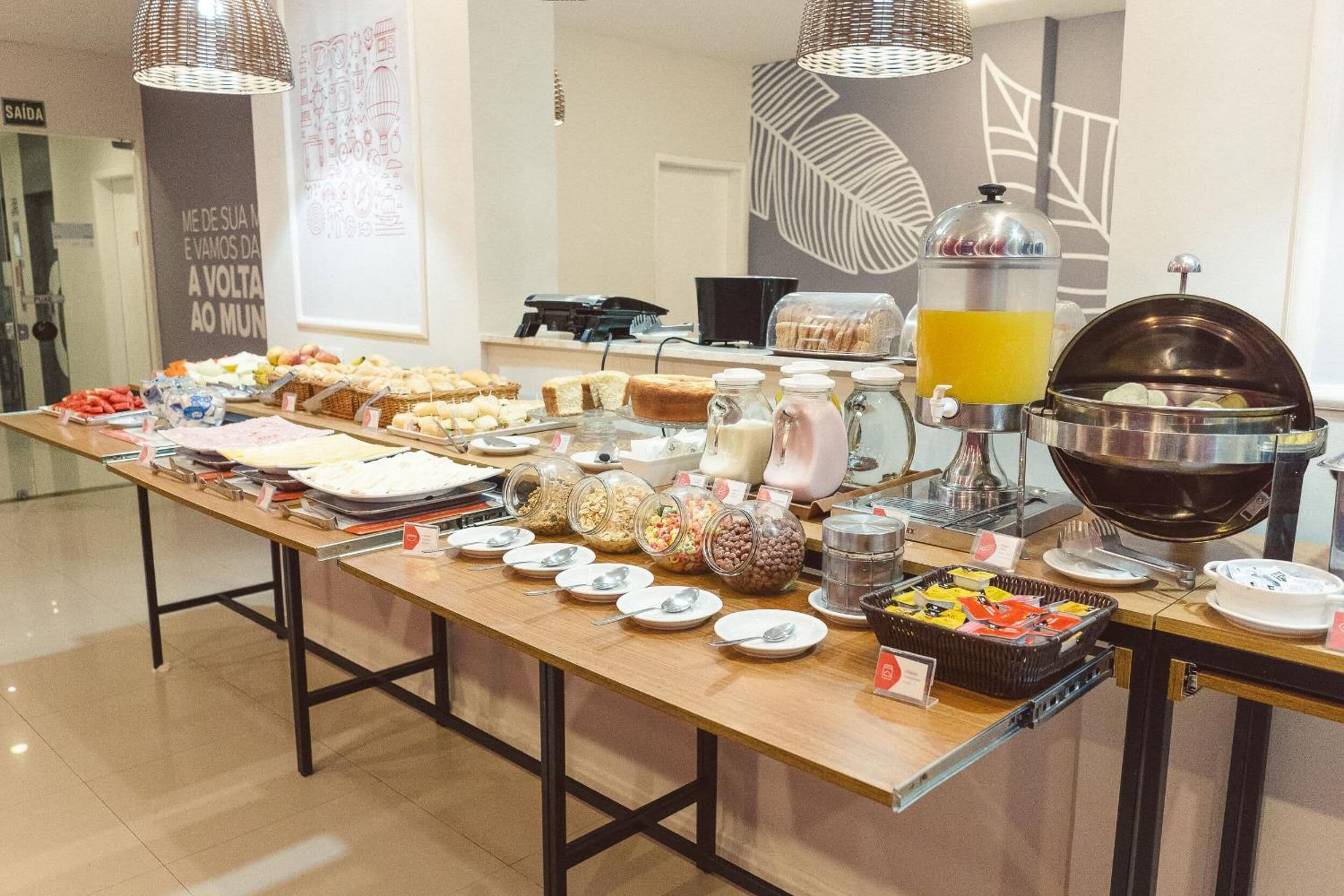 A buffet table with various food items and beverages, including jars of cookies, a coffee machine, and a juice dispenser.