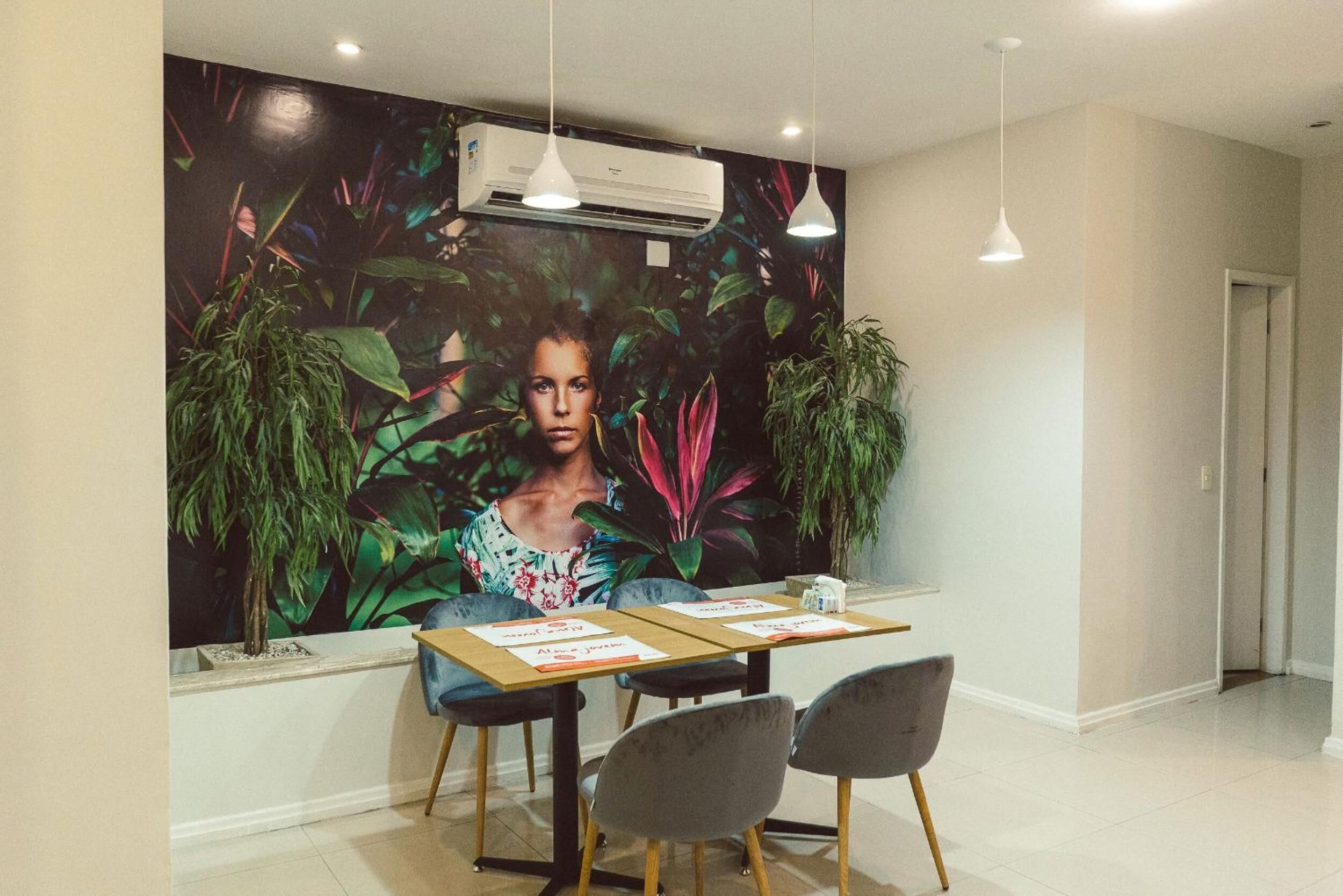 A dining area with a mural, a table with chairs, and an air conditioning unit.